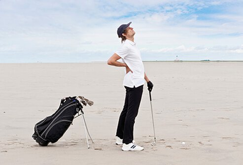 A man suffering low back pain while golfing.